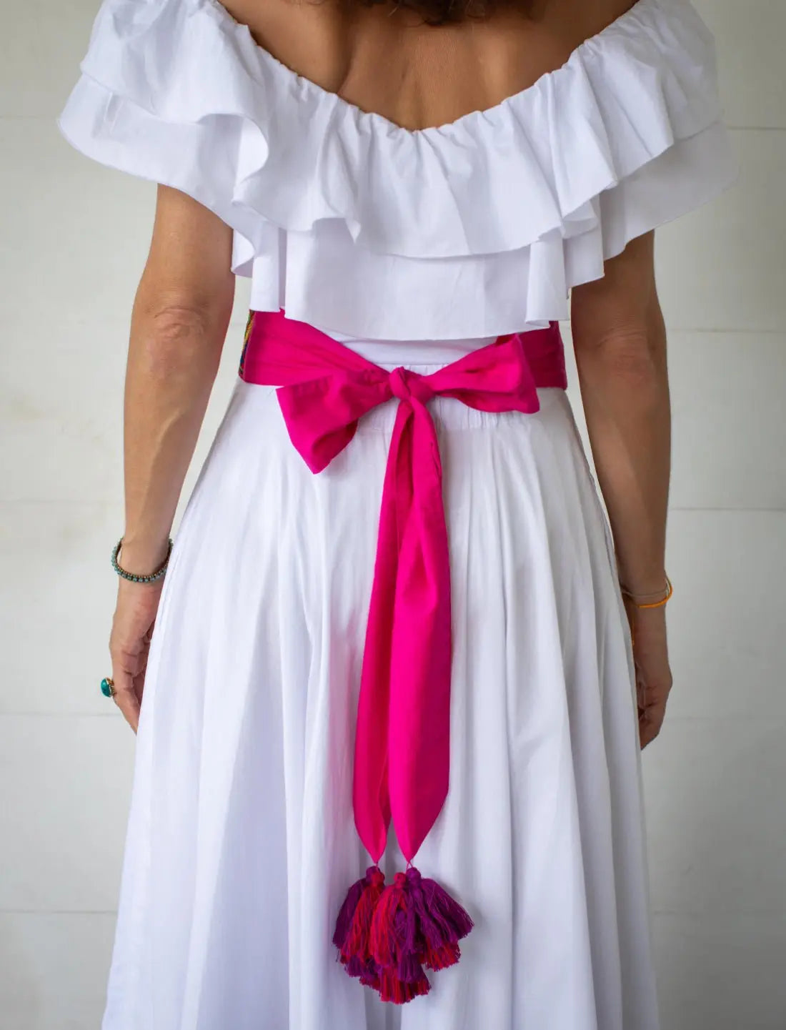 The back view of the model displays how the Golden Dawn Embroidery Belt neatly ties into an adjustable bow in the back. The end of the sash features vibrant tassels.