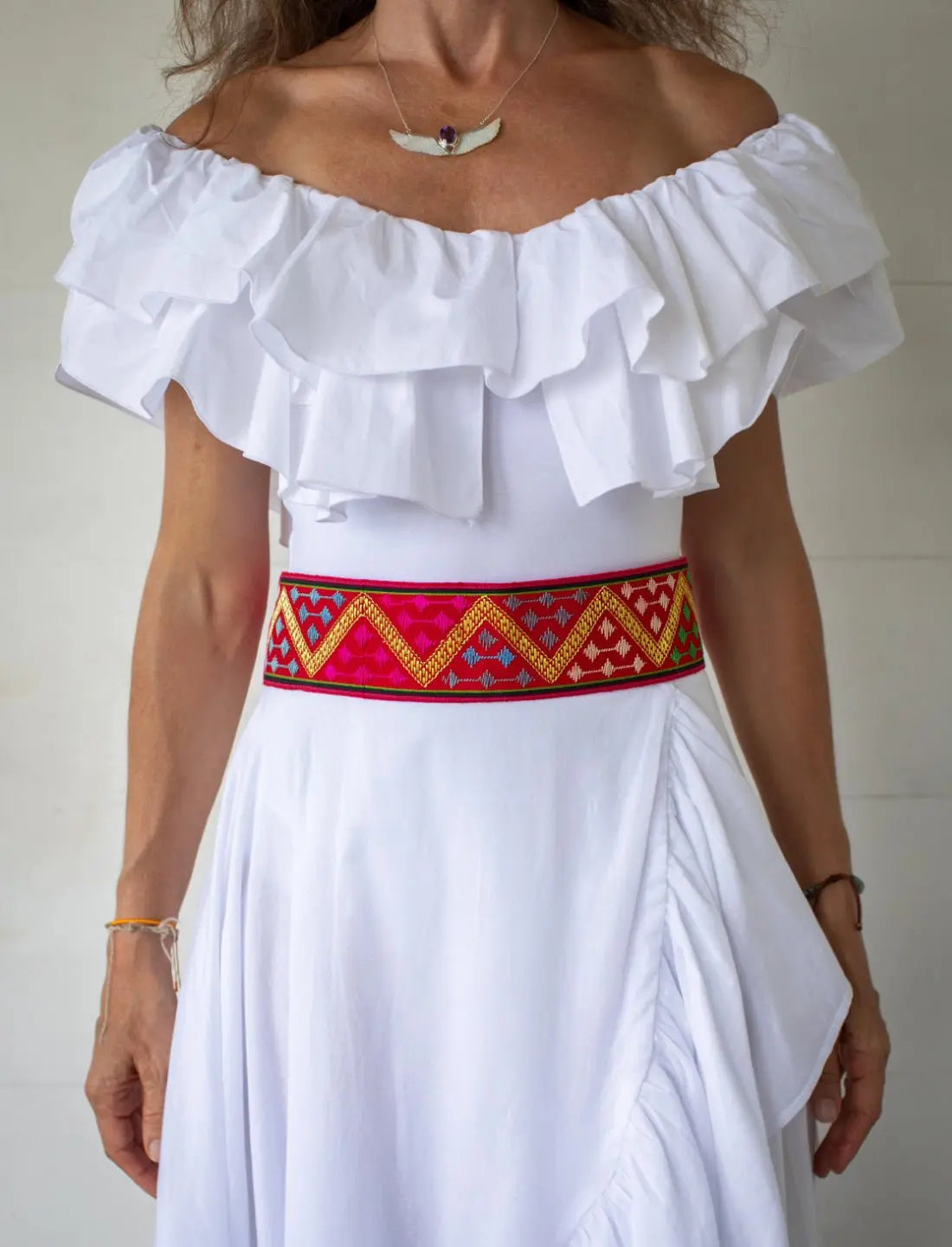 The model wears the Golden Dawn Embroidered Belt across her waistline. The colorful handwoven silk weave displays a beautiful, golden zig zag motif. 